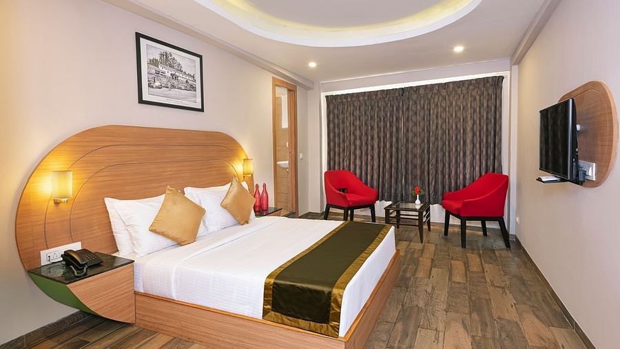 An image of a bedrom with dube sized bed and chairs on a different corner  | Mango HIll Central, Ooty
