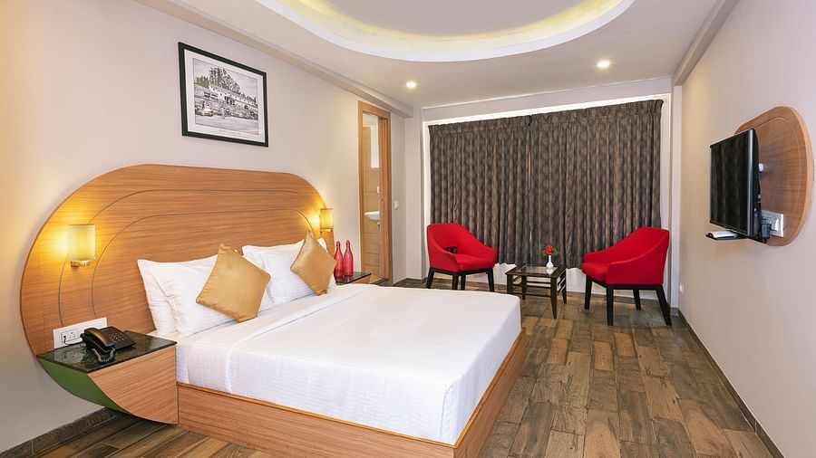 An image of a bedrom with dube sized bed and chairs on a different corner  | Mango HIll Central, Ooty