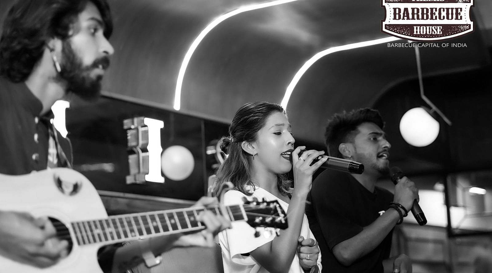 An image of two people singing on the stage while one person is playing a guitar - Themis Barbecue 