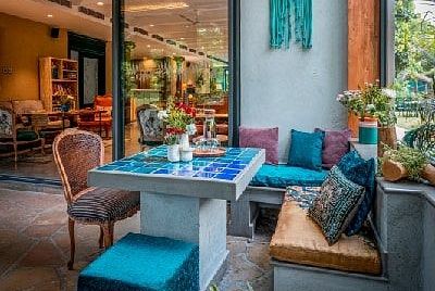 Outdoor seating area at Karma Chalets with cushioned benches, chairs, and plants under a wooden canopy.