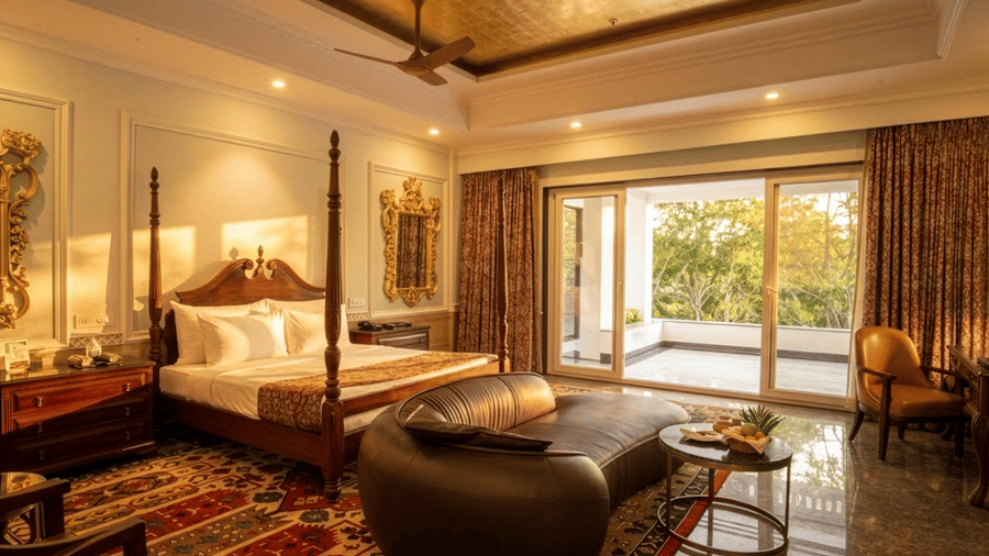 Luxury Deluxe Suite at MAYFAIR Oasis Resort Jharsuguda featuring a four-poster bed, ornate rug, and private balcony.