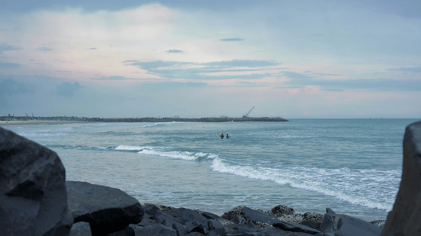 Gentle waves roll towards the rocky shoreline beneath soft afternoon light by sea