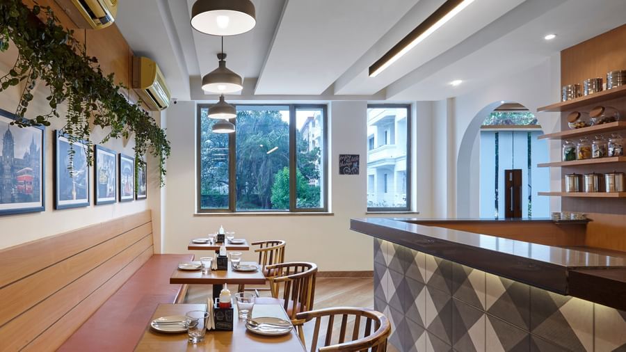 The dining area at Monday Hotels Mahape, Navi Mumbai, featuring a counter with bar stools and a view of the outdoors.