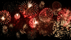 Red and gold fireworks exploding simultaneously across the dark night sky