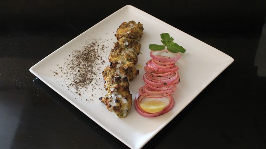 alt-text Chicken Malai Tikka with onion rings, lemon and mint leaves on the side