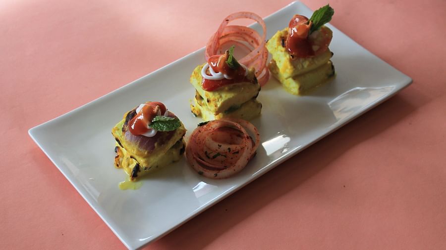 alt-text Paneer tikka on a plate with onion rings and mint leaves topping