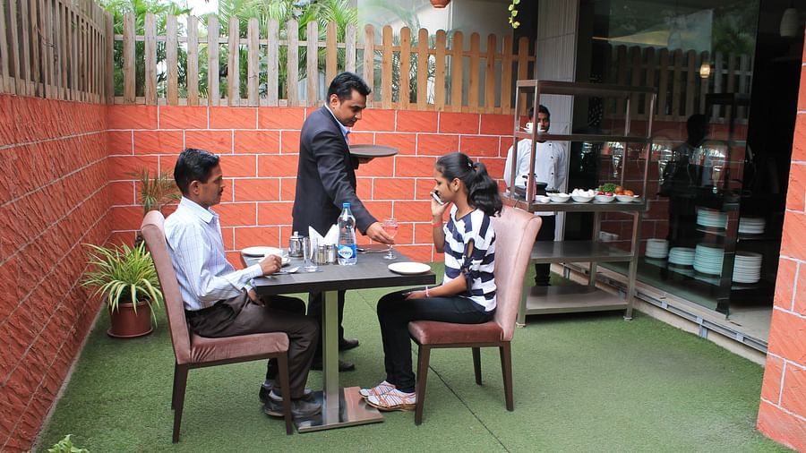 alt-text A waiter serving food to two people seated at the table