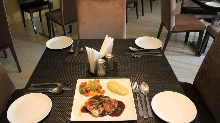 alt-text Grilled chicken with pan-tossed veggies and mashed potatoes served on the table with cutlery