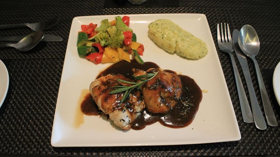 alt-text Grilled chicken with pan-tossed veggies and mashed potatoes served on the table with cutlery