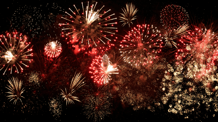 A display of red and gold fireworks exploding in the night sky, with many different bursts filling the frame.