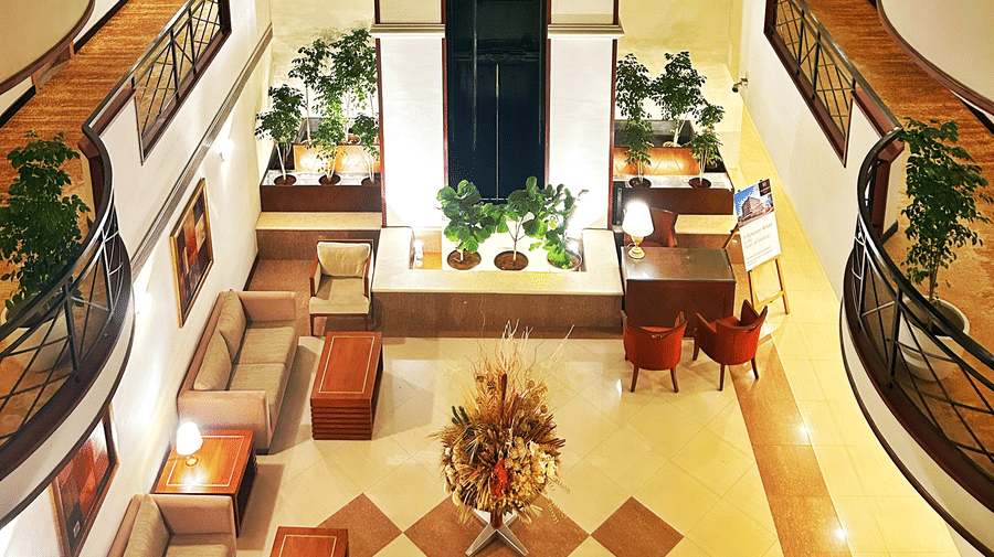 The Residency Karur | A seating area with sofas, several floors, and plants.