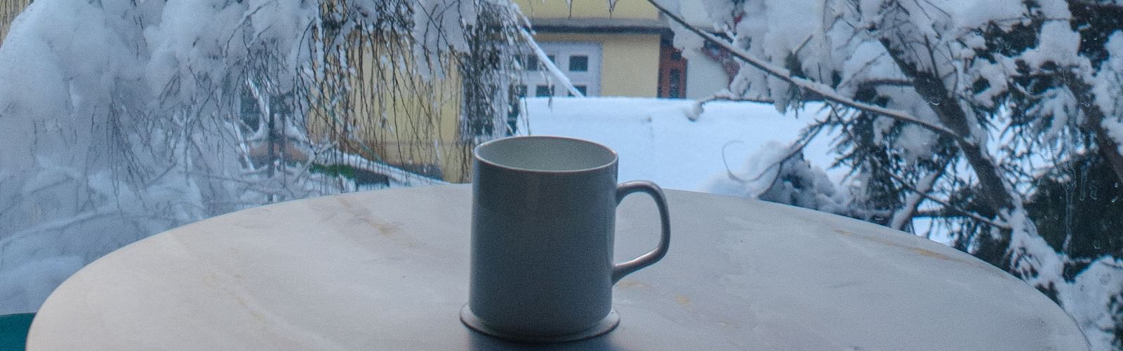a mug on a table with snowy trees in the background