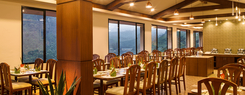 Restaurant interior highlighting the wooden pillars, exposed beams, and pendant lighting - Abad Copper Castle, Munnar