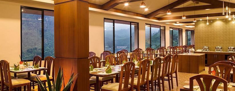 Restaurant interior highlighting the wooden pillars, exposed beams, and pendant lighting - Abad Copper Castle, Munnar