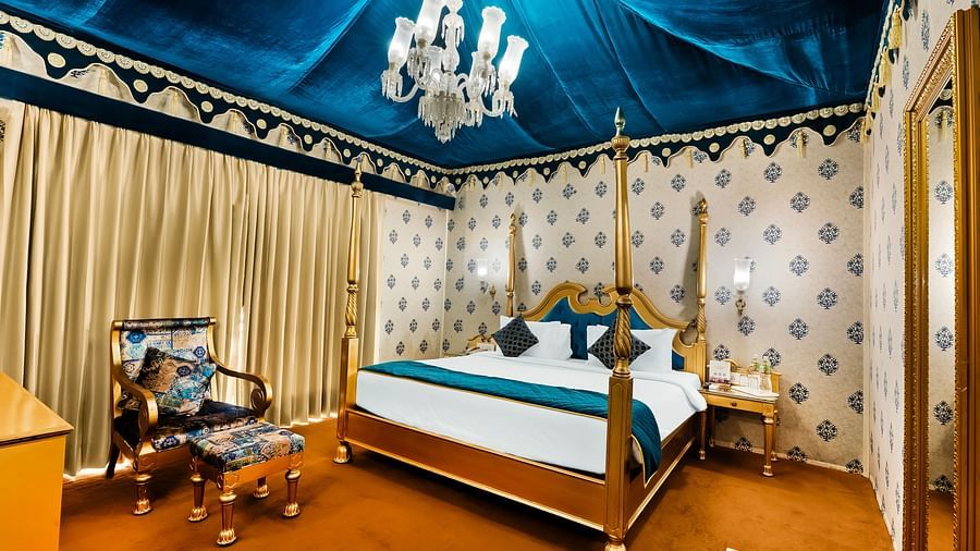 An overview of a tent with a double bed, a chair and a small table - Rajasthali Resort & Spa, Jaipur.