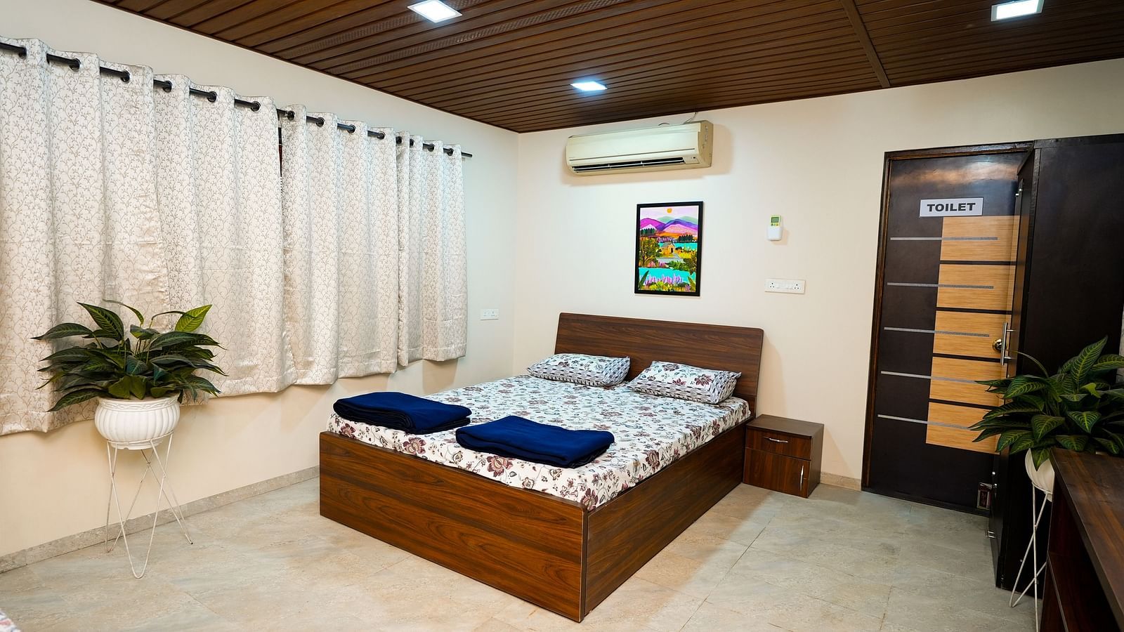 Modern and cozy bedroom interior with wooden furniture and plants |  Diamond Parks, Pune - Pune Places to Stay