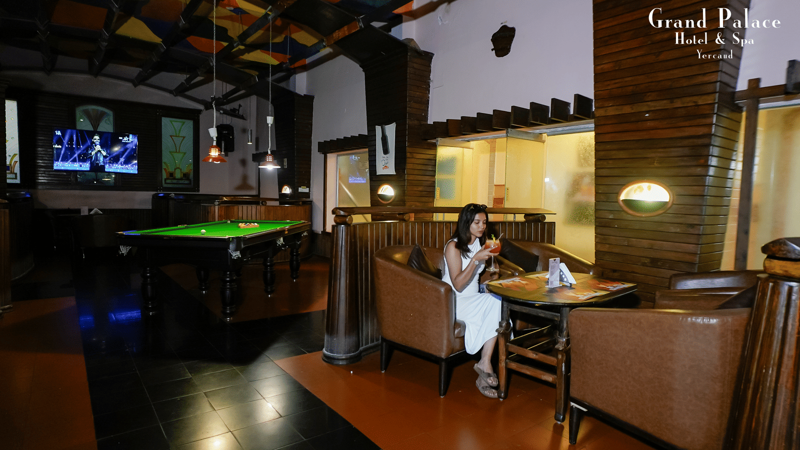 Alt text: Cloud-9 Bar at Grand Palace, Yercaud, featuring warm wood décor, cushioned chairs, dining tables, open seating, and elegant ceiling lights.
