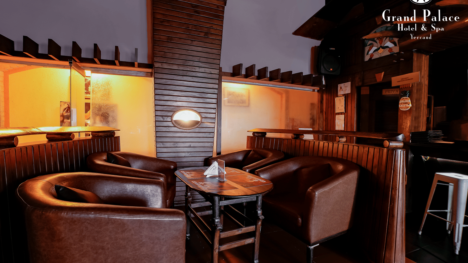 Seating area inside Cloud-9 Bar at Grand Palace, Yercaud showing bar stools, tables, and partitioned booths.