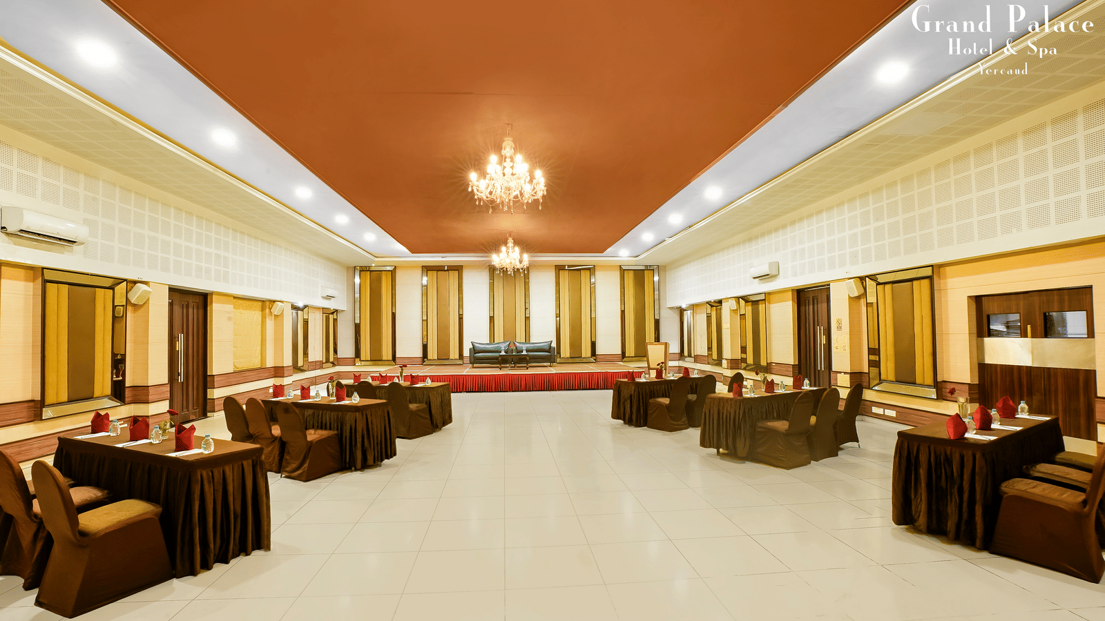 Large event space at Grand Palace, Yercaud arranged with sofa seating, open area, chandeliers, panoramic windows, and polished flooring for gatherings