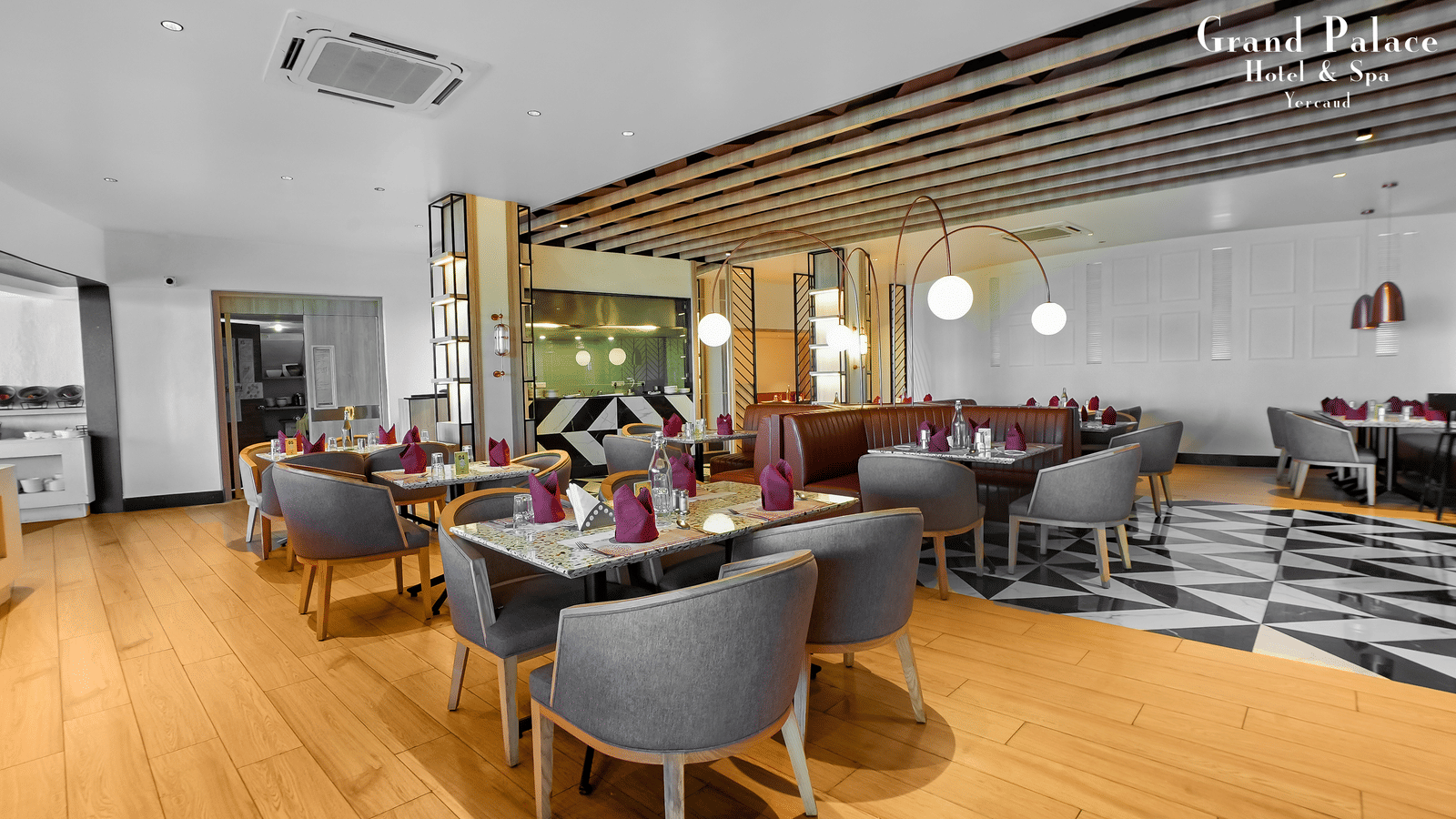 Orange Restaurant at Grand Palace, Yercaud showing dining setup with tables, chairs, buffet counter, and wooden flooring.