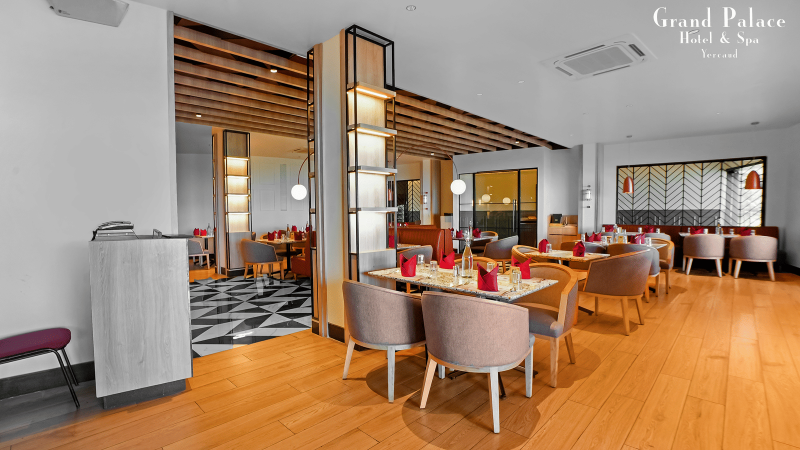 Indoor restaurant space at Grand Palace, Yercaud showing tables, chairs, open area, and buffet counter.