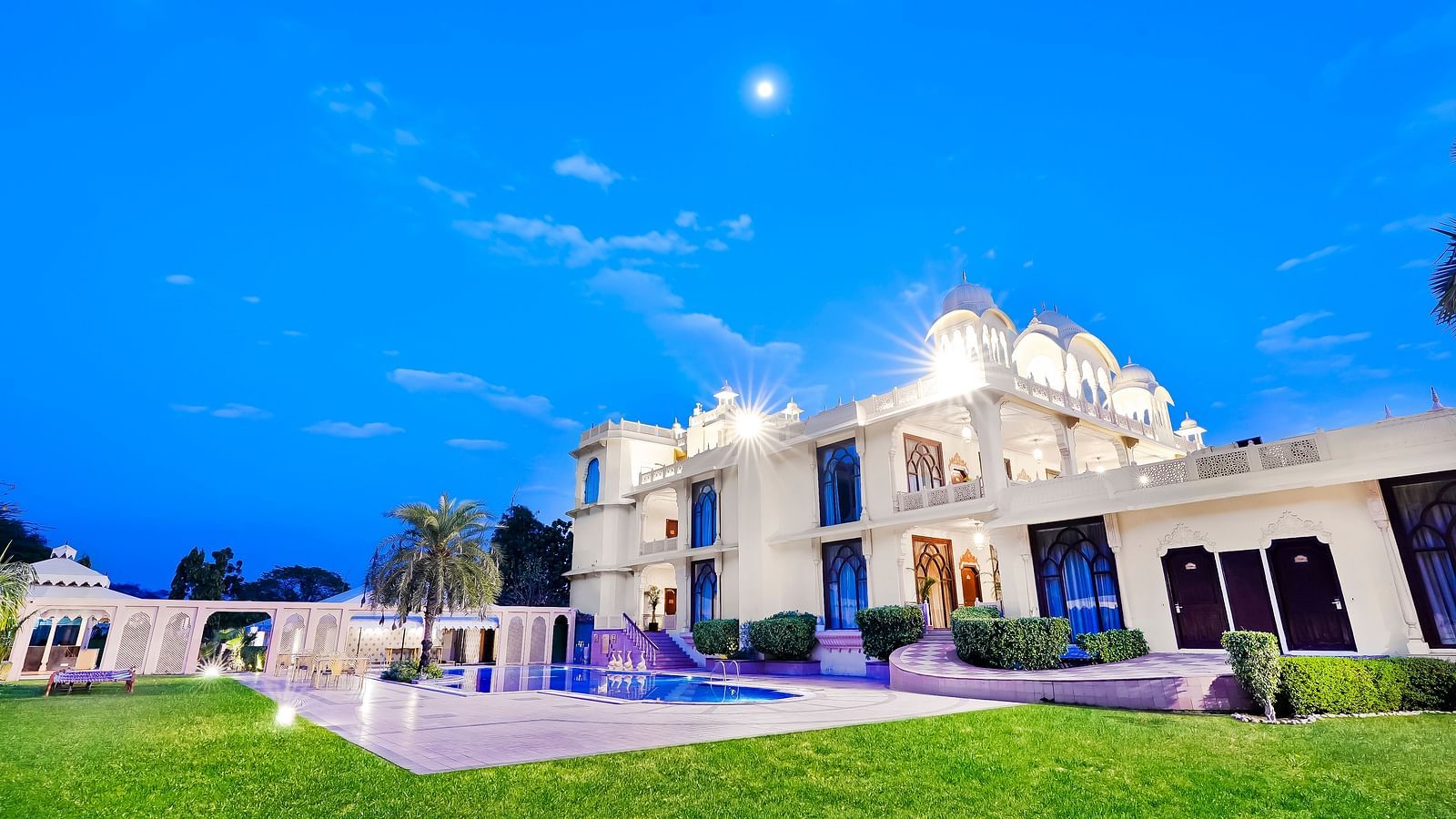 An overview of the facade of Rajasthali Resort & Spa, Jaipur with a swimming pool and lawn in view.