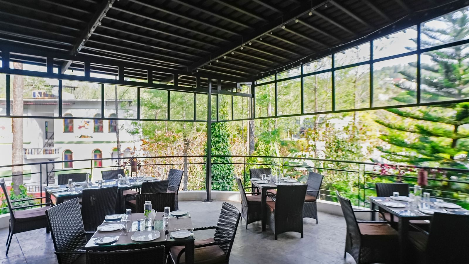 Covered outdoor dining area with tables and chairs neatly arranged at WOW Bungalow, Yercaud. 