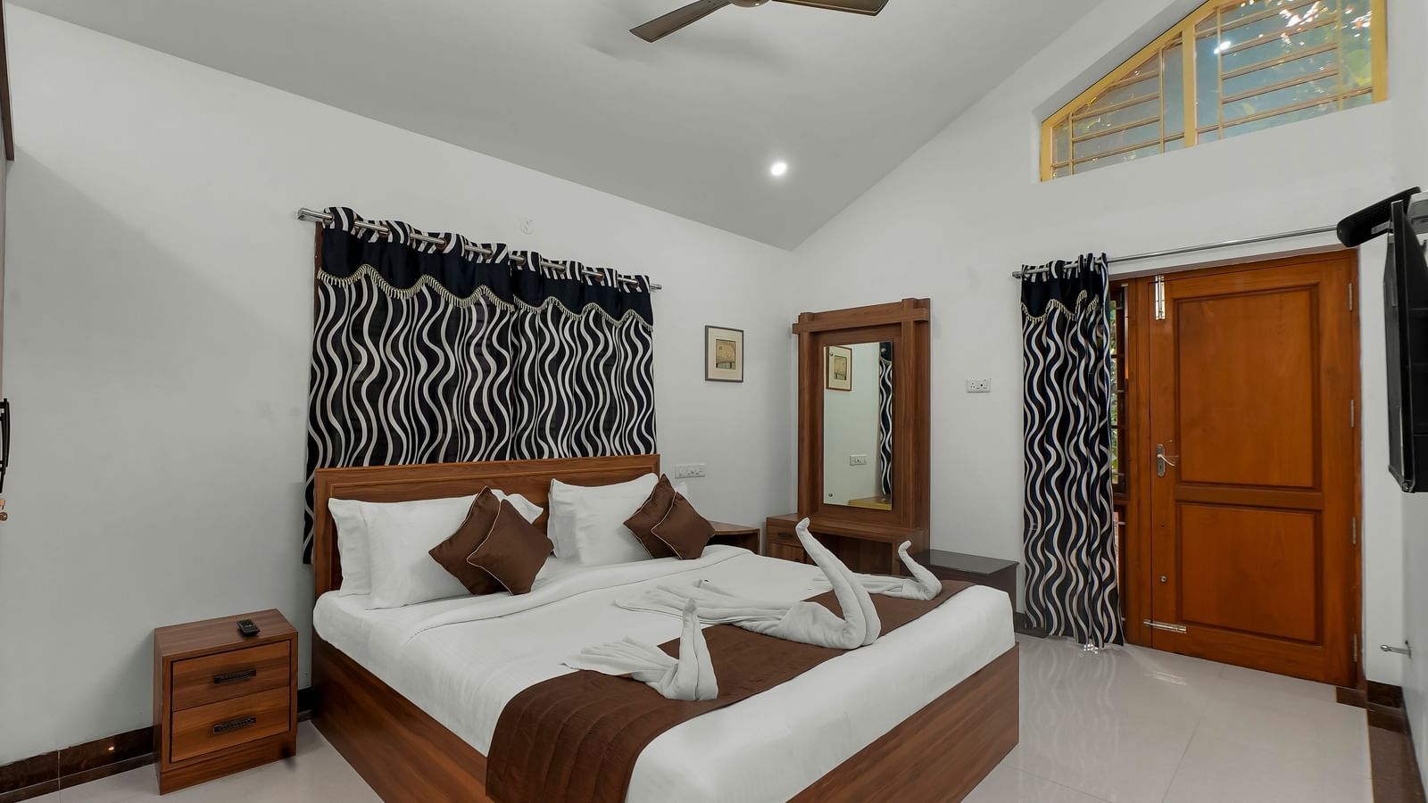 Diagonal view of a room showing a large bed with towel decorations at WOW Bungalow, Yercaud. 