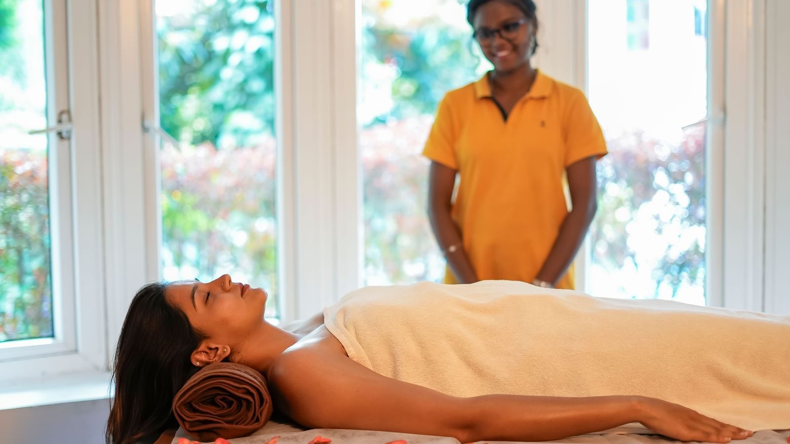 A lady lying on a spa bed and a therapist standing beside her at WOW Bungalow, Yercaud.