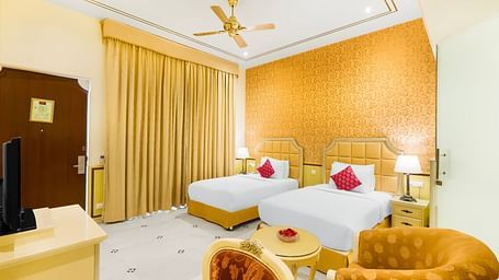 An overview of a room with two single beds, a chair and a table in view - Rajasthali Resort & Spa, Jaipur.