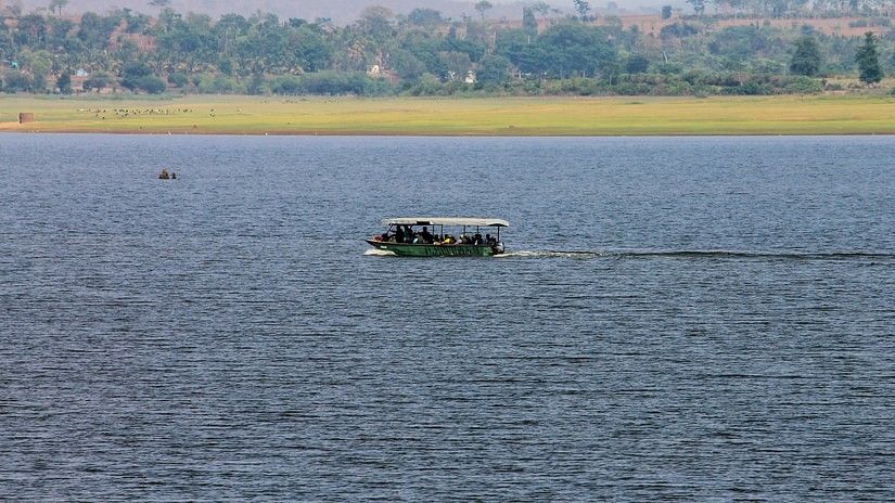 An image of a boat in the middle of a river surrounded by greenery