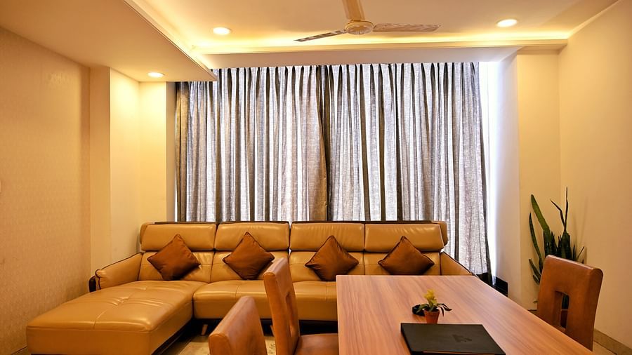A cosy living room with a large beige sofa and a wooden floor - TGI Insignia, Bhopal