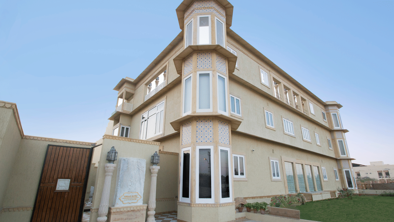 Exterior of Sonaar Haveli featuring traditional Jharokha-style windows, patterned stonework, and a manicured lawn.