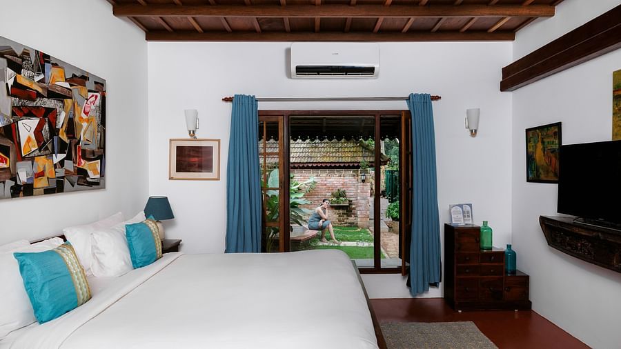 A shot of a room with bed, a flat screen TV, and a window overlooking the view - BluSalzz Villas - Muhamma Resort, Alleppey