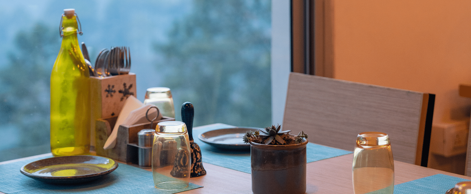 Restaurant table set with a glass bottle and plates at BluSalzz Escapade Resort, Lansdowne.