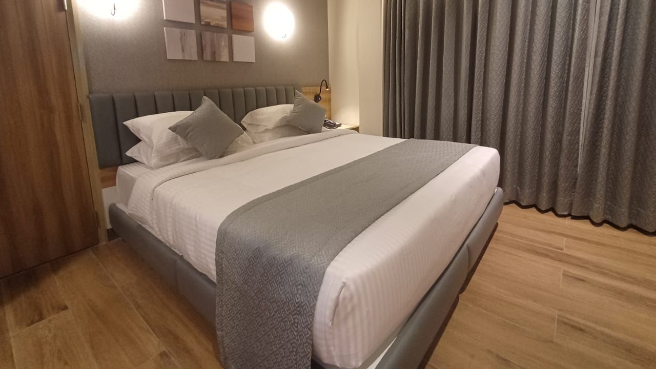 Family Suite at Hotel Paai, Hosur featuring a double size bed, a wardrobe, and a window with curtains drawn.