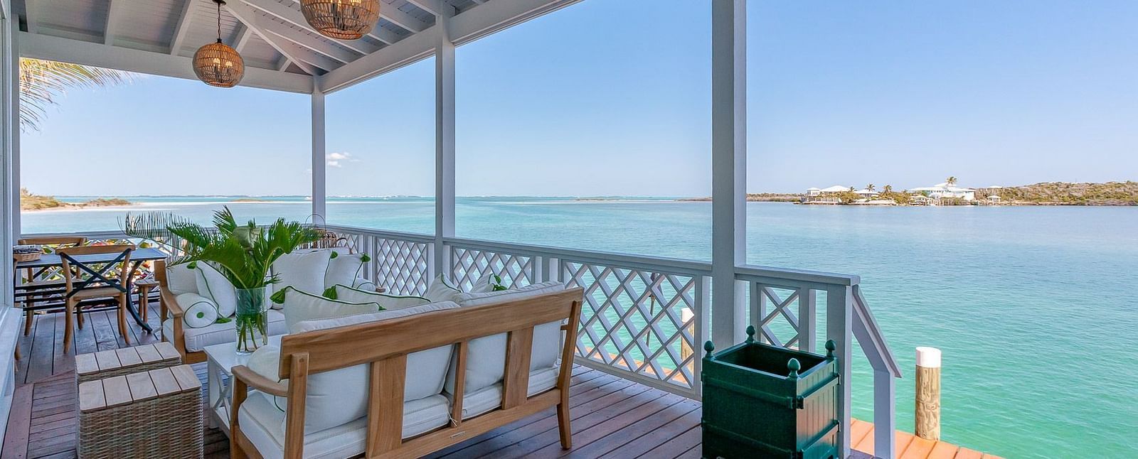 Spacious balcony with cushioned seating, wooden flooring, and panoramic ocean views under a clear blue sky | Abaco Inn