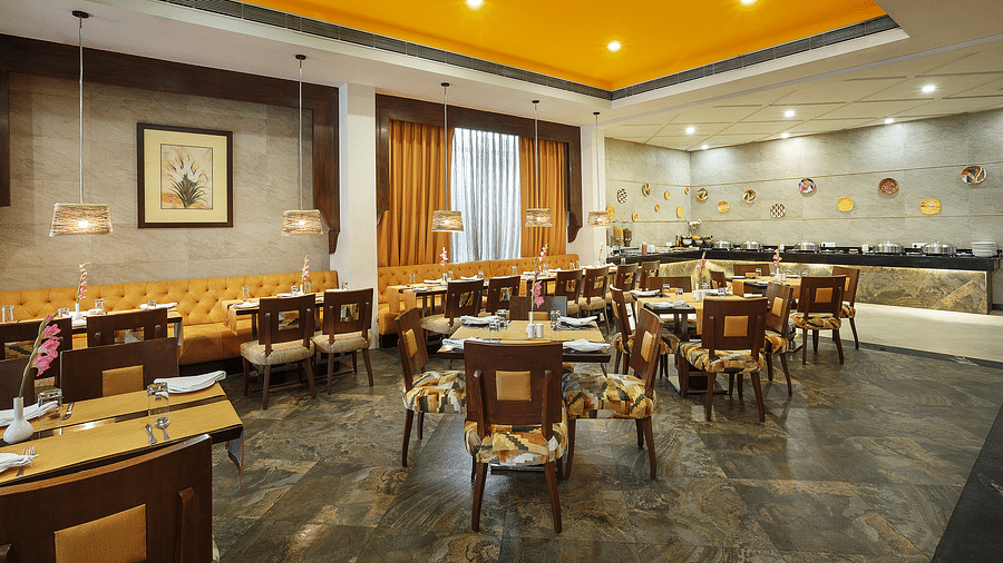 A bright and inviting dining space with yellow ceiling, stylish lighting and chair seating for guests - The Manor, Bareilly