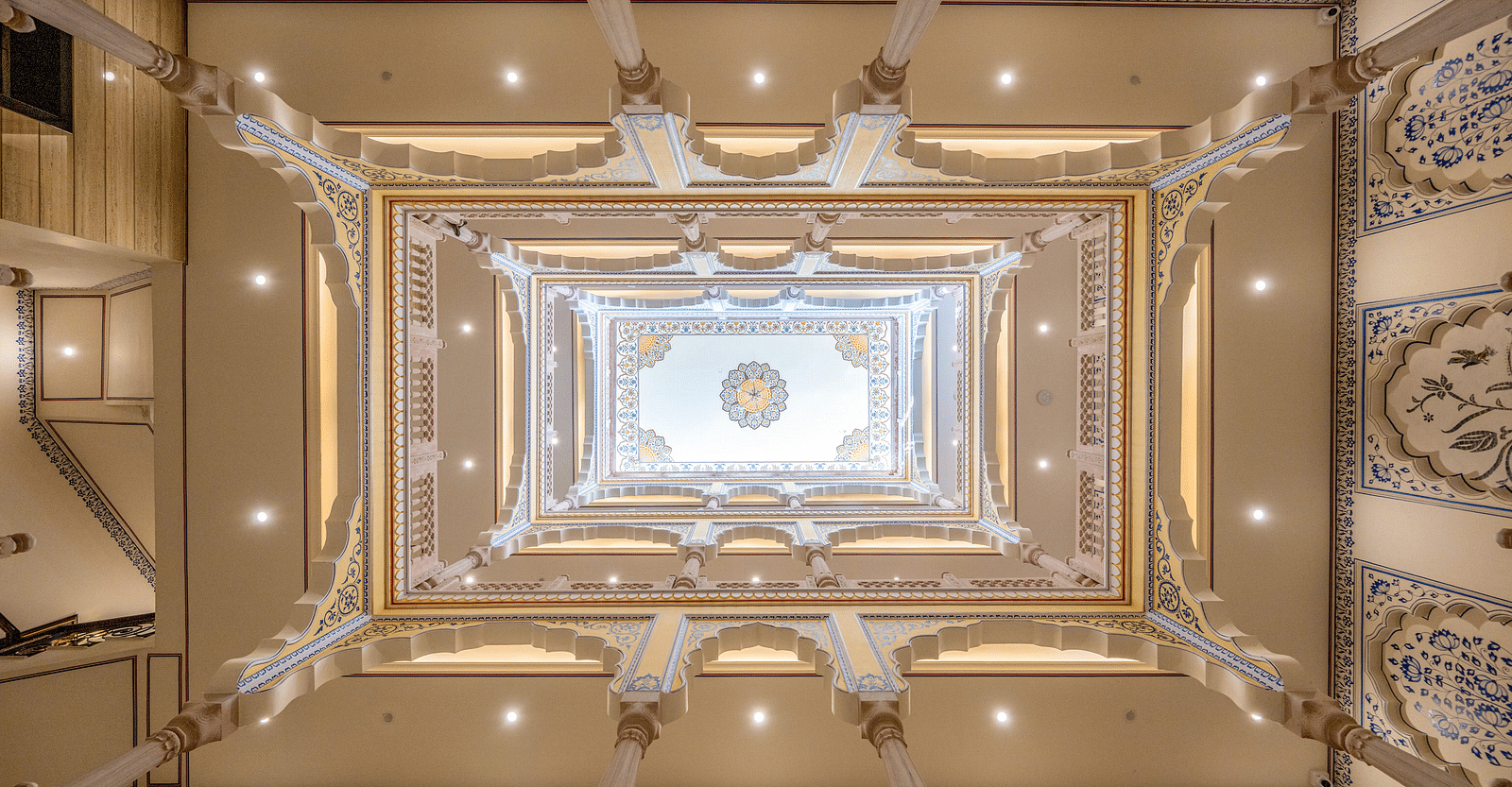 a beautiful atrium above the lobby of our hotel going four levels up with intricate paintings on the wall - Brij Castle, Jaipur