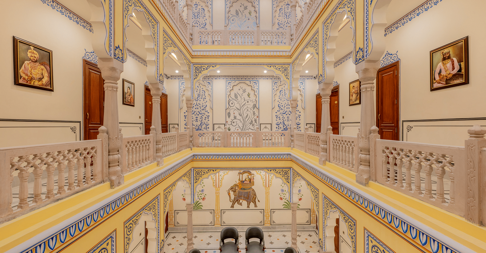 full view image of the corridor with beautiful miniature style painting done on the side walls and pillars of the first level - Brij Castle, Jaipur