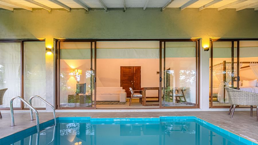 View of a room and pool area through floor-to-ceiling windows.