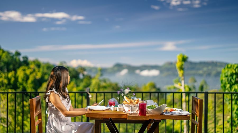 A side view of a person dining at a table in a balcony with mountain view during the day | Celestial Hills, Kandy