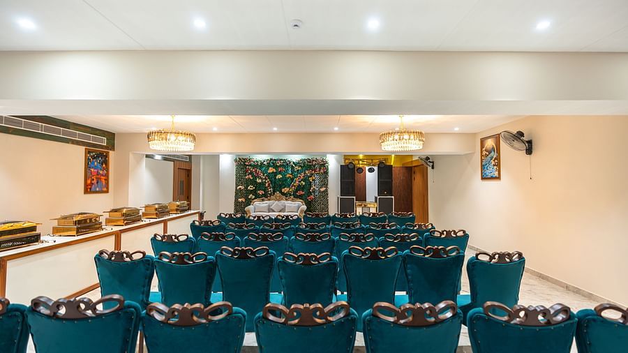 A banquet hall with blue chairs arranged and a stage -Pearl Hall