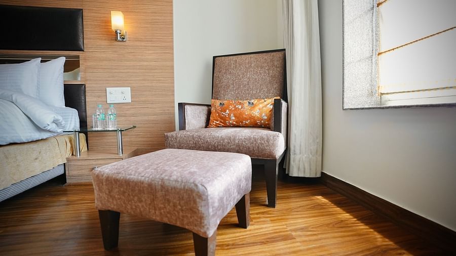A room with stools, a framed picture, and a bedside lamp, showcasing a cosy interior - VITS Gurugram