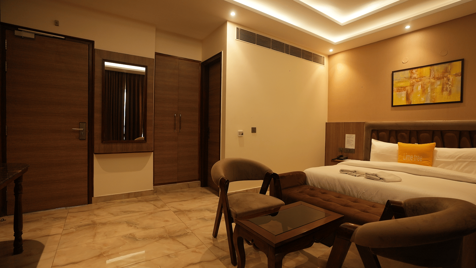 Entry view into a luxury hotel suite showing a tiled floor, dark wood panelling, and a seating area.