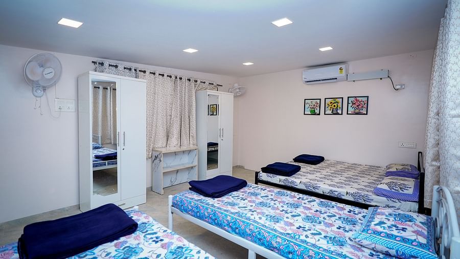 Shared dormitory room in a hostel with multiple beds and bright blue bedding | Diamond Parks, Pune 