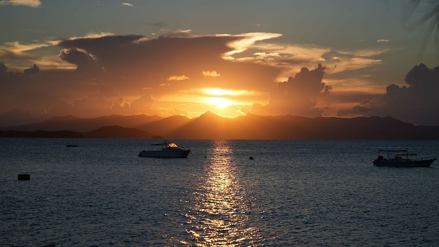 Sunset over the sea with boats on the water near Flower Island Resort.
