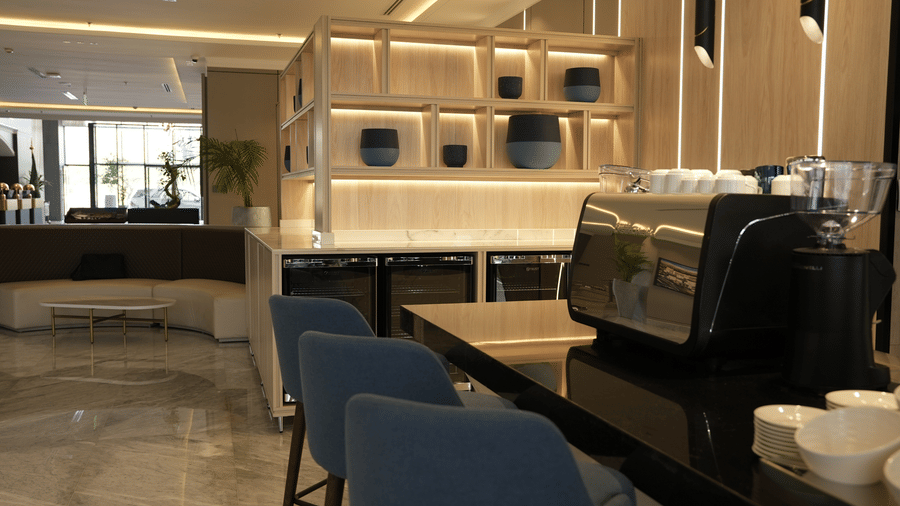 Grand Iva Cafe seen with ambient lighting, modern decor shelves adorned with earthen pots. A coffee machine is seen in the foreground.