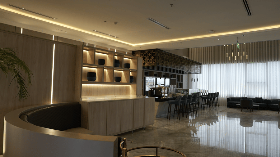 Grand Iva Cafe at Grand Iva Hotel, Abha, seen with ambient lighting, modern decor, a counter with a coffee machine on it and bar stools placed beside it.