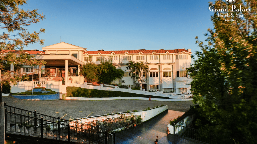 Grand Palace, Yercaud with view of  main building, walkway, fence and green garden surrounding the hotel.